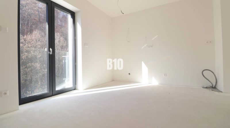 An empty room in a 3-room apartment with large windows and a view of nature.