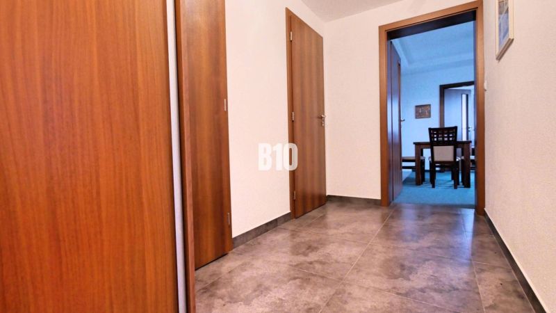 A hallway with tiles and doors leading to a room in a 3-room apartment.