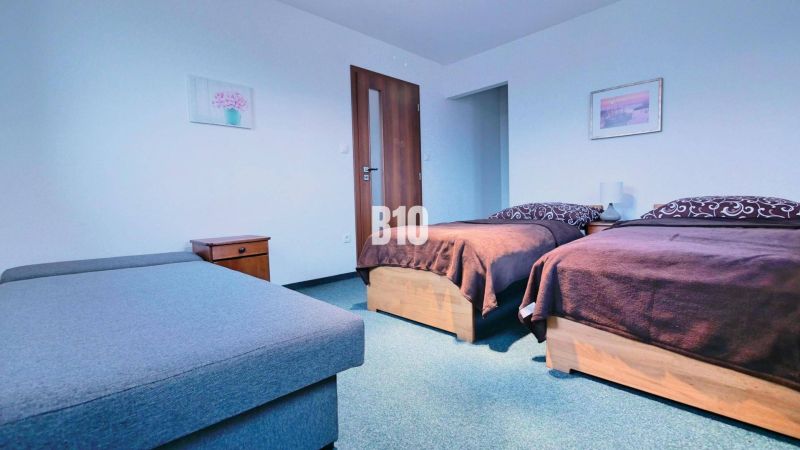 Bedroom in a 3-room apartment with two beds, nightstands, and a sofa.