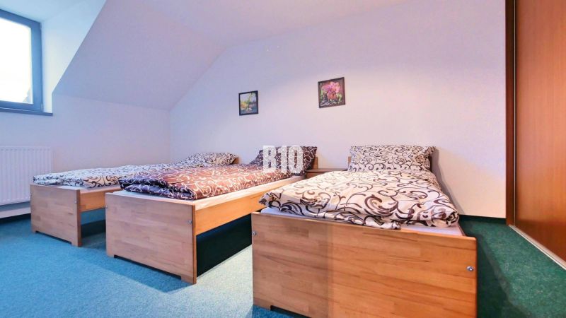 A bedroom with three beds in a 3-room apartment. Wooden decorations, green carpet.