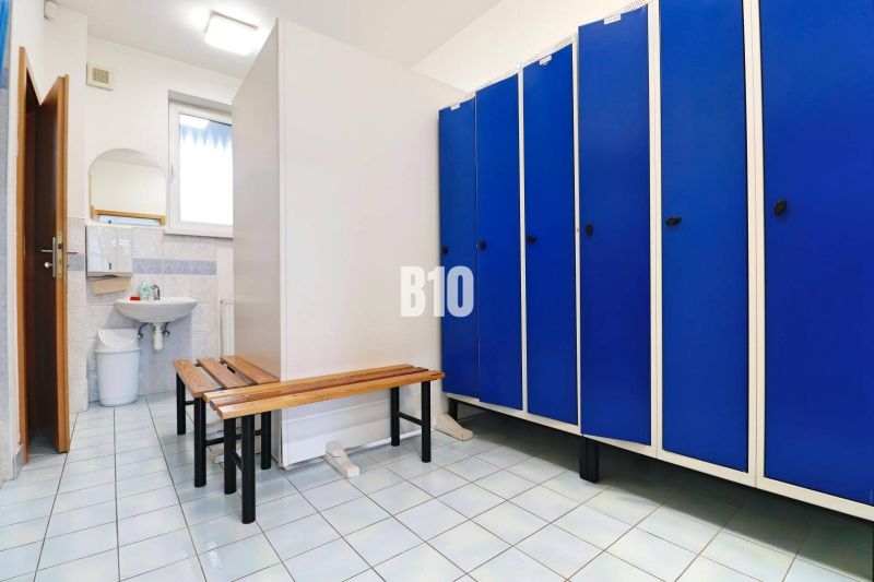 Locker room in the production area with blue lockers and a mirror above the sink.