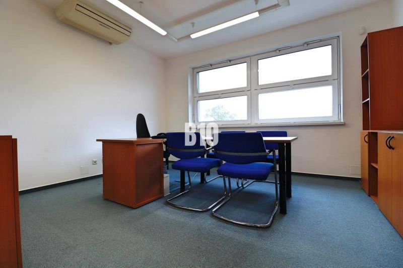 Offices with blue chairs, a table, white walls, and windows.