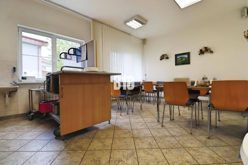 A dining area in a production facility with wooden chairs and a sink.
