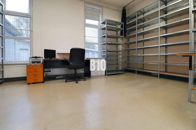 Office in a production area with shelves, a computer, and a chair.