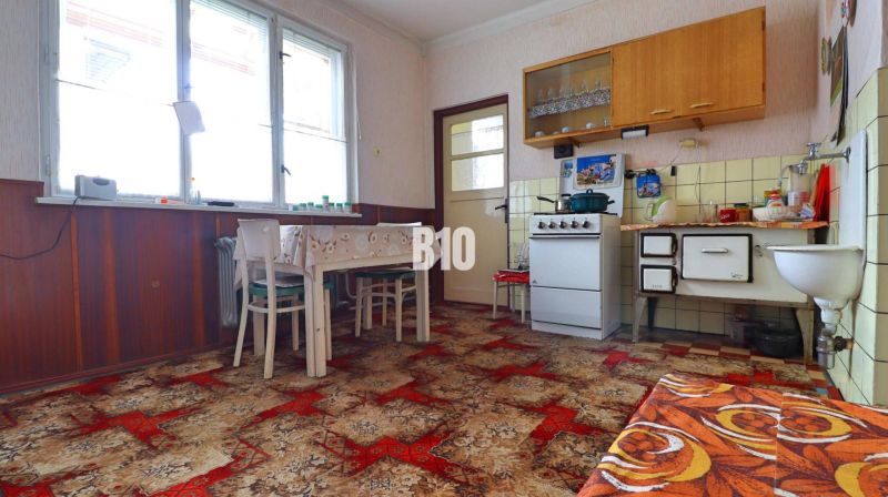 A kitchen in a family house with retro furniture, tiles, and a bold carpet.