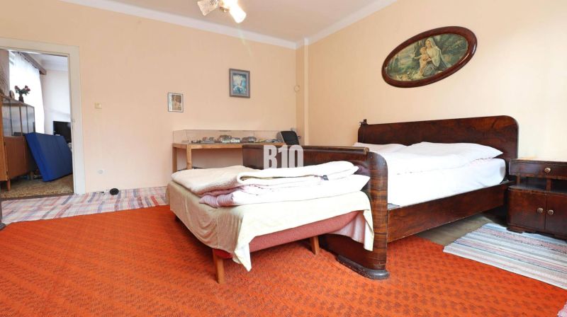 The interior of a family house with two beds, wooden furniture, and an orange carpet.
