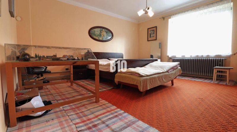 A room in a family house with a bed, a table, a model railway, and carpets.