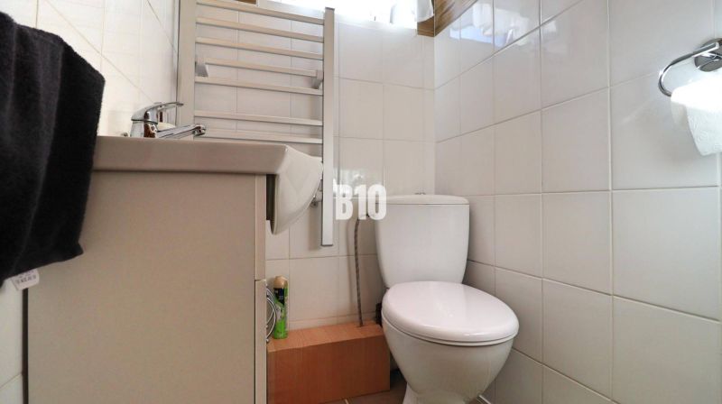 Bathroom in a family house with white tiles, a sink, and a toilet.