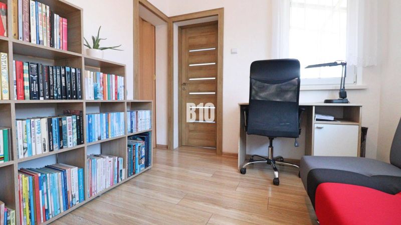 Library, desk, and chair in a family house with a wood-patterned floor.