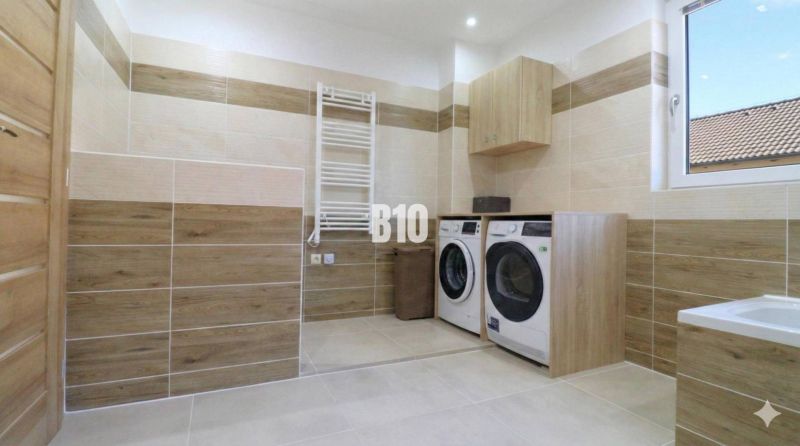 Laundry room in a family house with a washing machine, dryer, and a wooden decor floor.