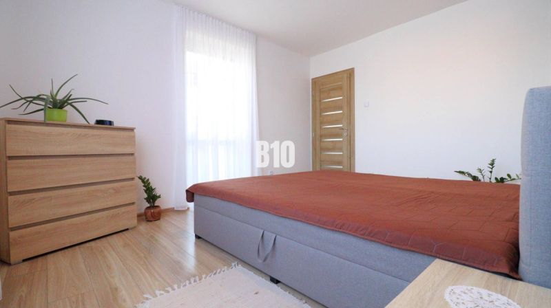 A bedroom with a bed, wardrobe, and plants on a wooden floor decor in a family house.