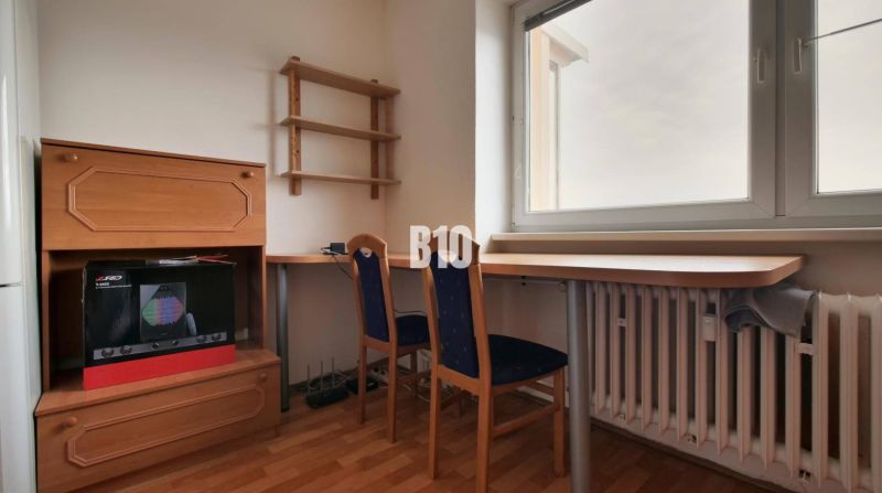 A workspace with furniture and a chair, a floor with a wooden decor, a wall with a shelf.