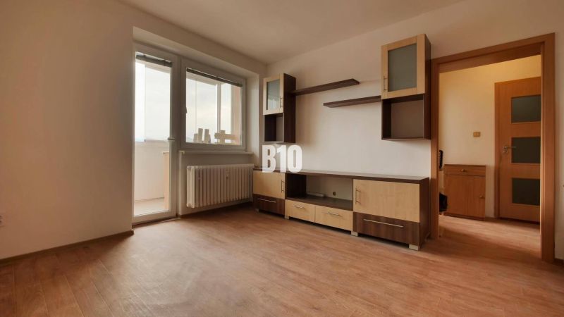 A room with furniture, a wooden decor floor, balcony doors.