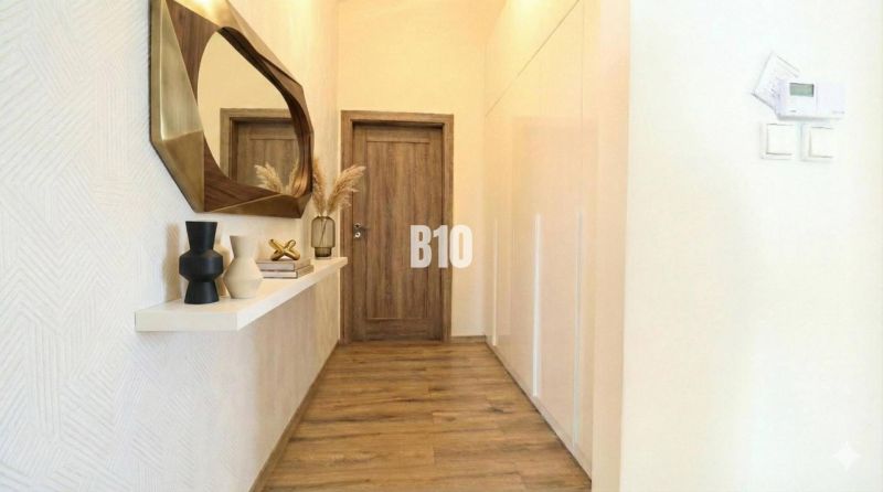 Narrow hallway in a family house with a wooden decor floor and a decorative mirror.