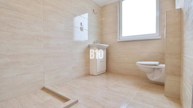 A bathroom with a sink and toilet in a family house with tiled walls.