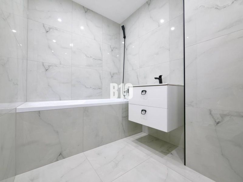 Bathroom with a shower and a sink with a cabinet in a 3-room apartment.