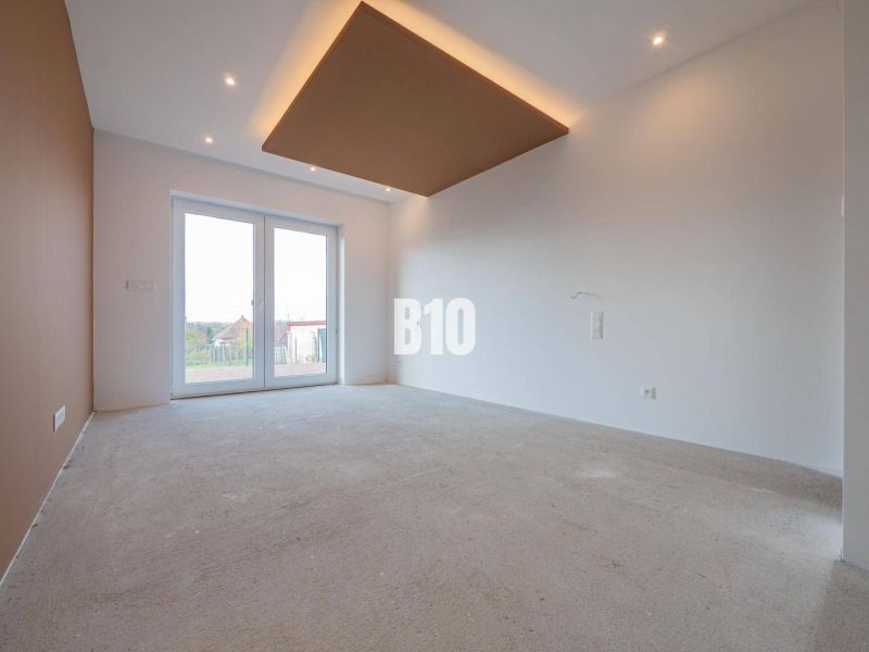 The interior of a family house with large windows and incomplete floor covering.