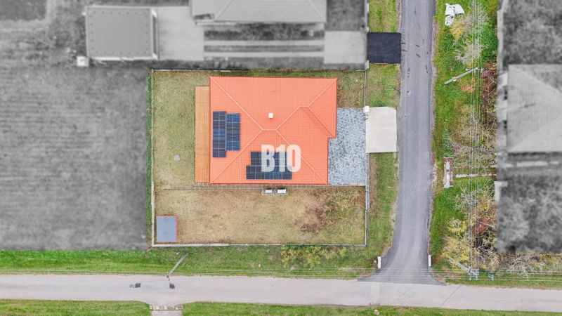 A family house in Beladice with a red roof and solar panels on a grassy plot.