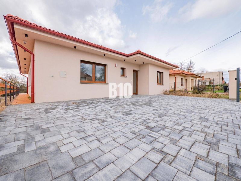 A family house in Beladice with a shingle roof and a large paved driveway.