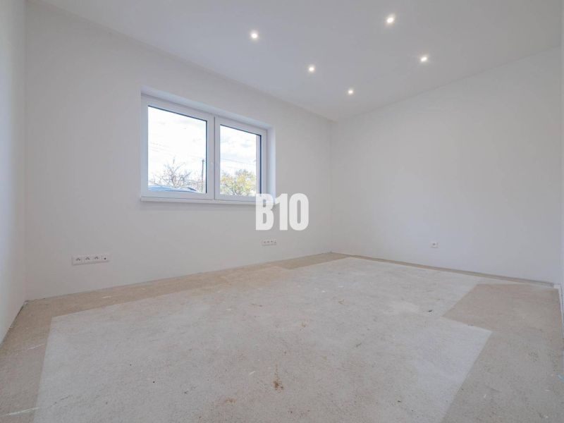 Empty room in a family house, white walls, large window, ceiling lighting.