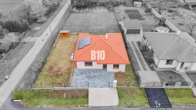 A family house in Beladice with solar panels on the roof and a landscaped plot.