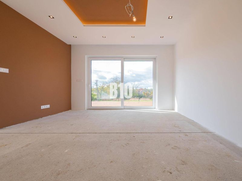 Living room of a family house with a brown wall and a large window without flooring.