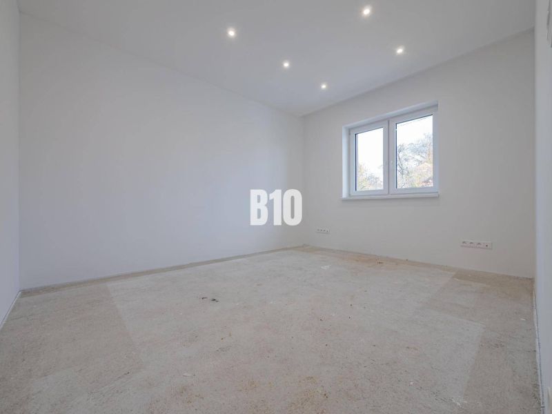 An empty room with white walls and a window, ready for flooring in a family house.