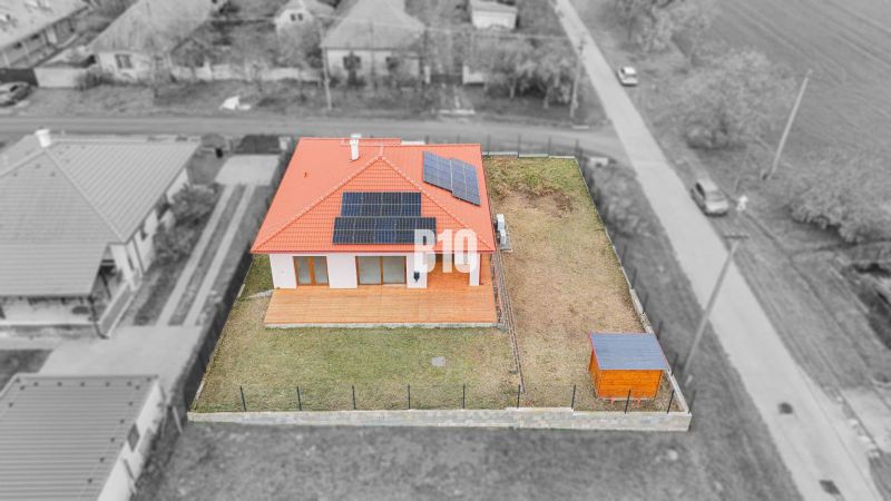 A family house in Beladice with solar panels and a fenced garden.