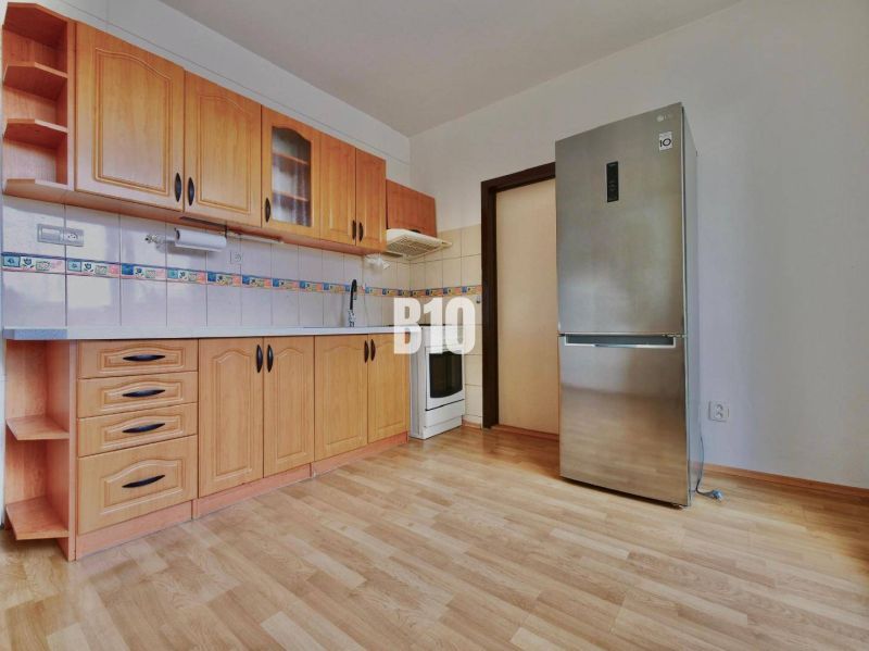A kitchen with wooden cabinets and a wooden decor floor in a 3-room apartment.