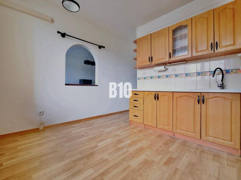 A kitchen in a 3-room apartment with a wooden decor floor and built-in cabinets.