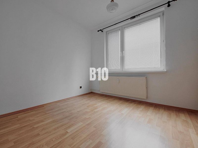 An empty room with walls in a 3-room apartment, a floor with a wooden decor, a large window.