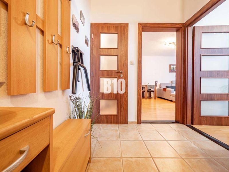 Entrance hall in a 2-room apartment with a wood-patterned floor and a coat rack.