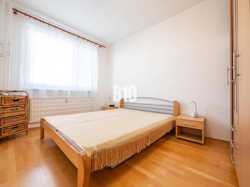 Bedroom in a 2-room apartment with a bed and a wooden decor floor.