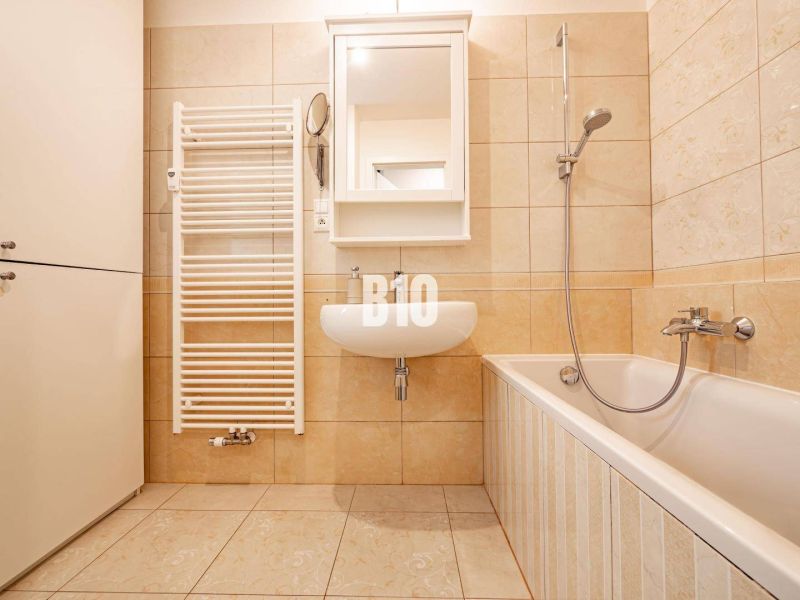 A bathroom with a bathtub and a sink in a 3-room apartment with tiles.