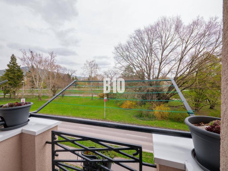 Balcony of a 3-room apartment in Nitra with a view of greenery and a row of trees.