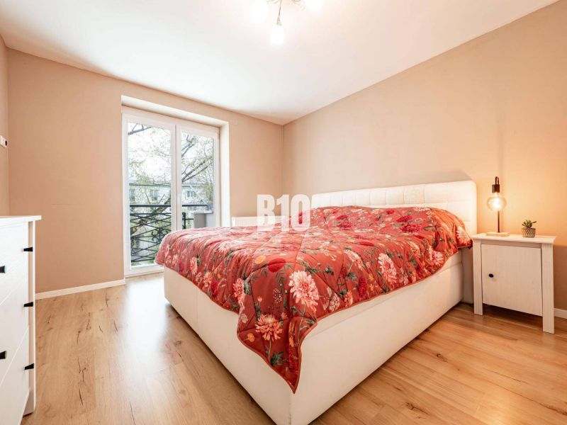 A bedroom in a 3-room apartment with a wooden decor floor and orange bedding.