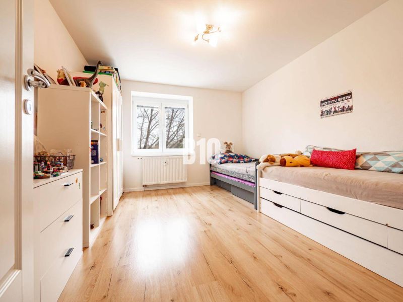 Children's room in a 3-room apartment with a bed, shelves, and a wooden decor floor.