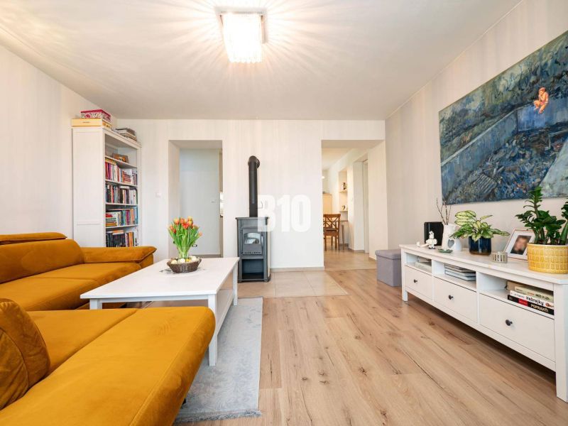Living room of a three-room apartment with a wooden decor floor and a comfortable sofa.