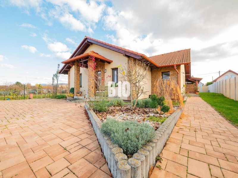 A family house in Nitra with a paved courtyard and a well-maintained garden under a blue sky.