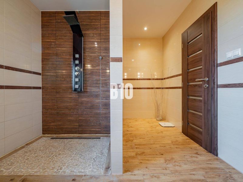 A bathroom in a family house with a wooden decor floor and a shower enclosure.