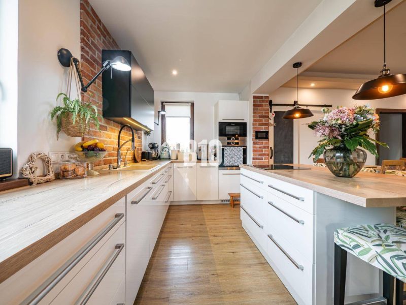 A kitchen in a family house with brick cladding and a wooden decor floor.