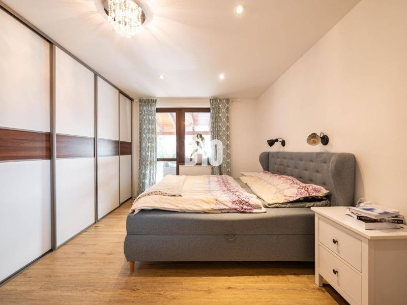 Bedroom with wood-patterned flooring, wardrobe, and upholstered bed in a family house.
