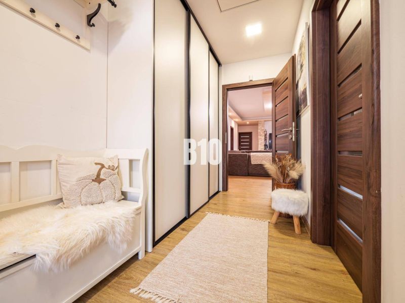 A hallway in a family house with a wooden decor floor, a bench, and cabinets.