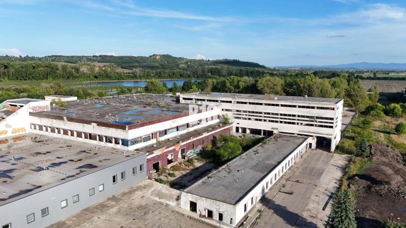 Production premises in Levice with abandoned buildings surrounded by nature and a body of water.