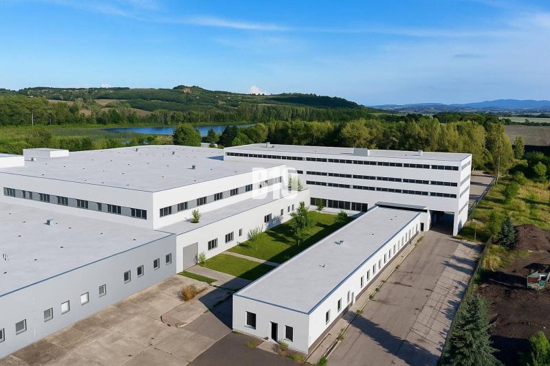 Production premises in Levice with a landscaped area, surrounded by greenery and a pond.