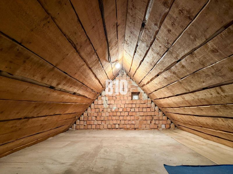 Attic space with wooden walls and a brick wall in a family house.
