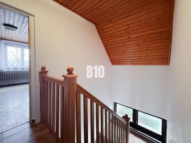 Family house with wooden railing, floor with wooden decor, and room with a window.