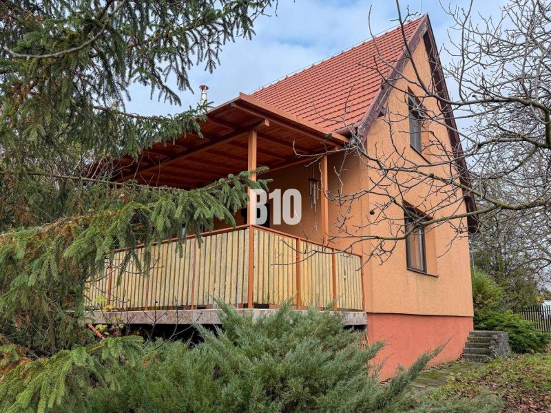A family house in Vlkas surrounded by greenery, traditionally sloped roof, wooden balcony.