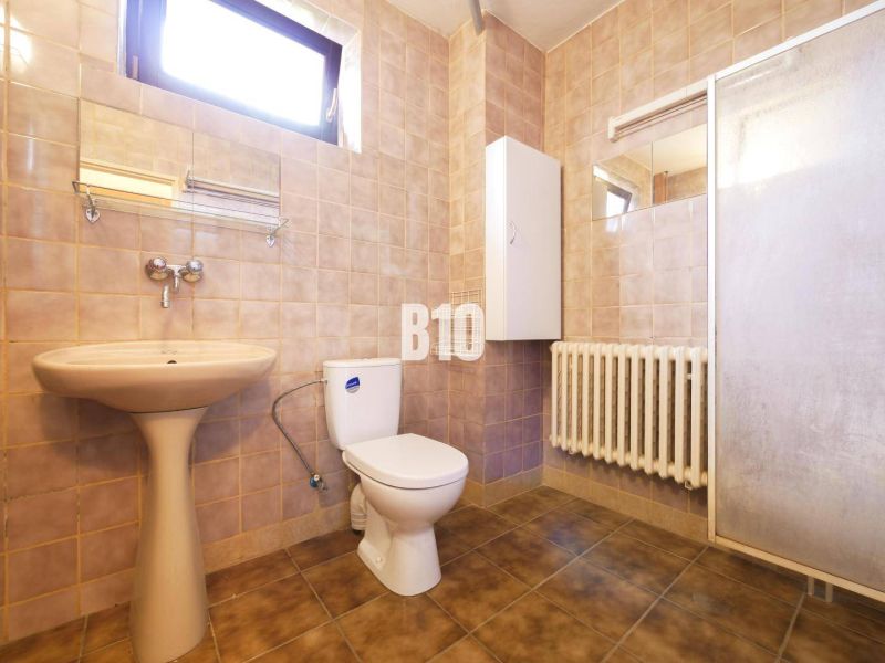 Bathroom in a family house with a sink, toilet, and shower. Tile decor.