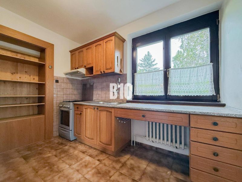 A kitchen in a family house with wooden cabinets and a large window, a floor with a wooden decor.